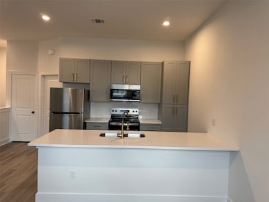 The open-concept living, dining, and kitchen area offers a seamless flow filled with natural light, featuring stylish vinyl plank flooring and a modern, inviting atmosphere perfect for everyday living or entertaining. The kitchen is fully equipped with stainless-steel appliances, sleek cabinetry, and ample counter space—combining functionality and elegance in one bright, contemporary space.