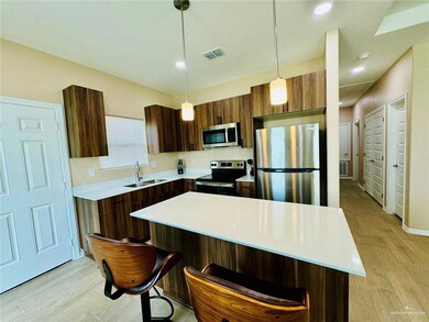 Kitchen featuring stainless steel appliances, light wood-style flooring, pendant lighting, a center island, and a breakfast bar
