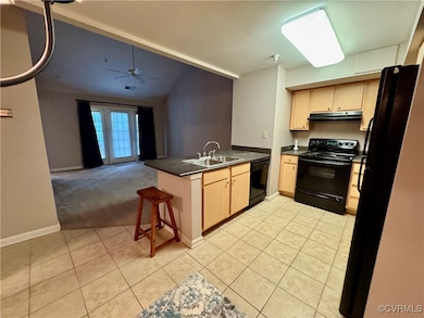 Kitchen with black appliances, a peninsula, light