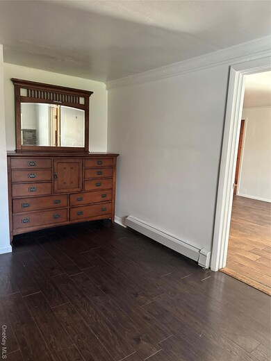 Bedroom featuring a baseboard heating unit and dark wood-style flooring