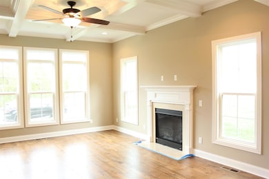 Elegant coffered ceiling with oversized fan and cozy gas fireplace.