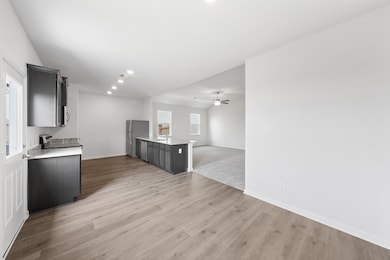 Kitchen with open floor plan, a peninsula, recessed lighting, light stone counters, and light wood finished floors