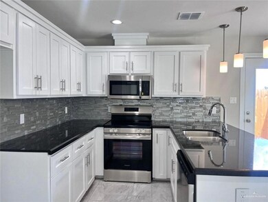 Kitchen with white cabinets, a sink, appliances with stainless steel finishes, a peninsula, and marble finish floor