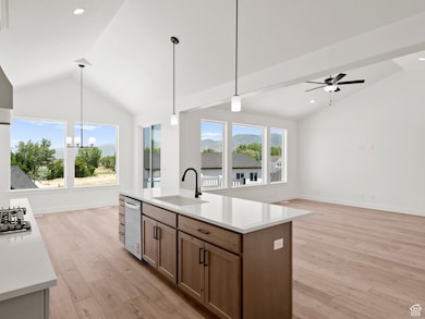 Kitchen featuring open floor plan, light countertops, ceiling fan, decorative light fixtures, and high vaulted ceiling