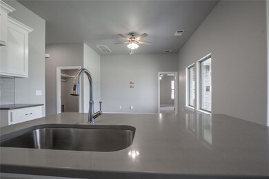 Kitchen featuring ceiling fan, white cabinets, sin