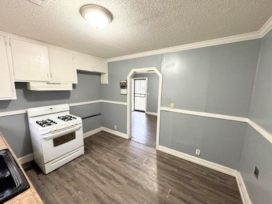 Kitchen with white gas stove, white cabinetry, dar