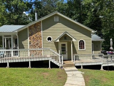 View of front of property with a deck, a front yard, and a metal roof