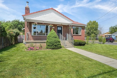 View of front of home with covered porch, a chimney, and brick siding