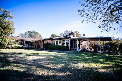 Rear view of house featuring a yard, a chimney, a patio, and brick siding