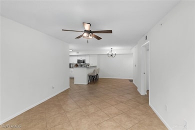 Unfurnished living room featuring a chandelier, light tile patterned floors, and ceiling fan