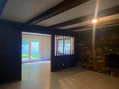 Unfurnished living room featuring beam ceiling and tile patterned floors
