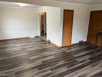 Unfurnished room featuring crown molding and dark wood finished floors