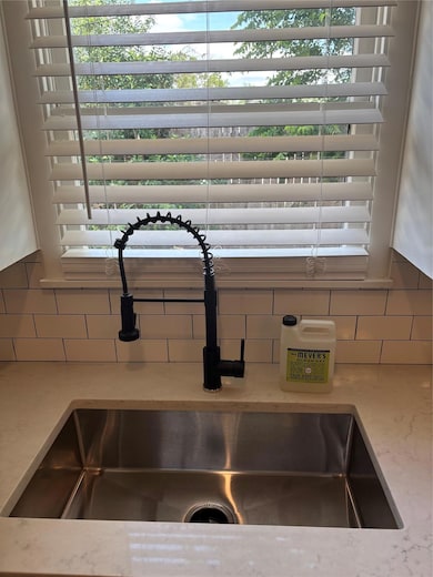 Kitchen view of backsplash, a sink, and light sto