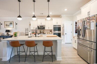 Kitchen featuring stainless steel appliances, tasteful backsplash, ornamental molding, and white cabinets