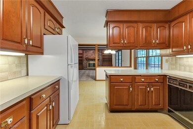 Kitchen featuring black dishwasher, backsplash, and light tile patterned floors