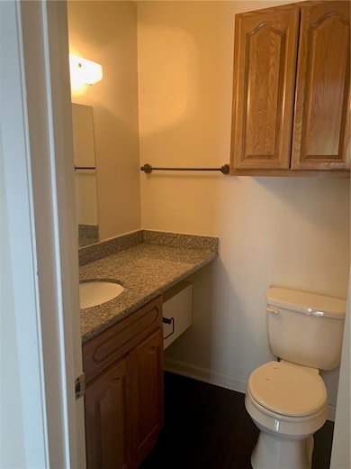 Half bathroom with baseboards, toilet, vanity, and