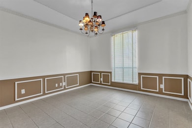 Spare room featuring a decorative wall, a wainscoted wall, light tile patterned flooring, and a chandelier