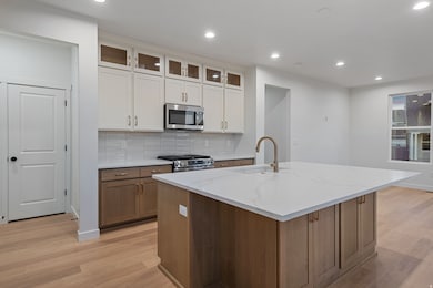 Kitchen featuring brown cabinets, decorative backsplash, recessed lighting, glass insert cabinets, and light wood-style floors
