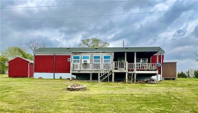 Rear view of house featuring a deck, a fire pit, and a yard