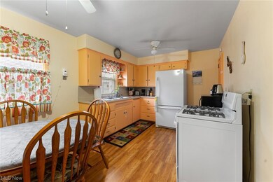 Kitchen featuring light wood-type flooring, light brown cabinetry, ceiling fan, sink, and white appliances