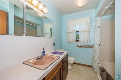 Full bathroom featuring tasteful backsplash, vanity, toilet, shower / bath combo with shower curtain, and baseboards