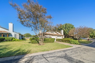 View of property hidden behind natural elements featuring a front yard, driveway, a chimney, and a residential view