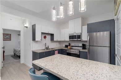 Kitchen with a sink, decorative backsplash, white cabinets, and stainless steel appliances