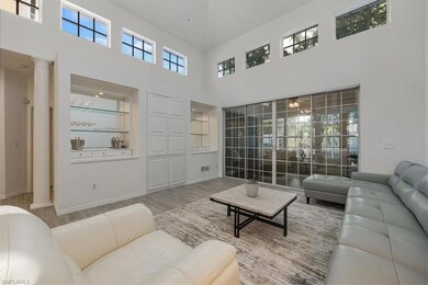 Living room featuring a towering ceiling, wood finished floors, and ornate columns