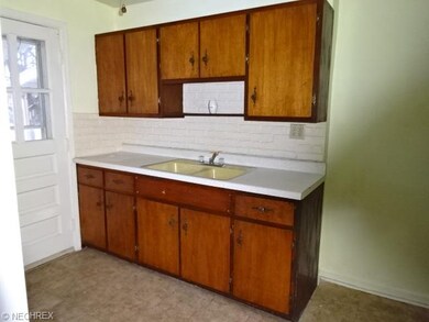 Kitchen with double sink and the door leads to wooden porch and backyard.