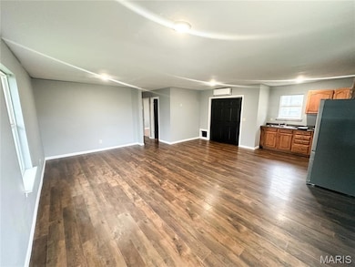 Unfurnished living room featuring baseboards and dark wood finished floors