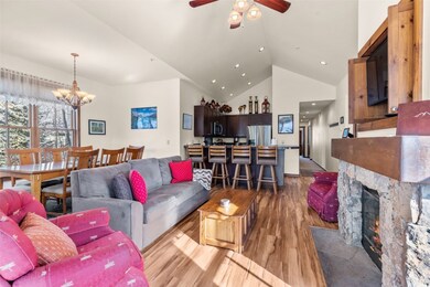 Living area with wood finished floors, high vaulted ceiling, ceiling fan, a chandelier, and a fireplace