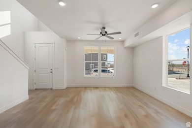 Empty room featuring light wood finished floors, ceiling fan, and recessed lighting