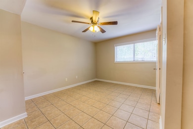 Empty room with a ceiling fan and light tile patterned floors