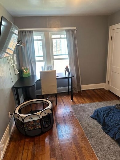 Bedroom with dark wood-type flooring and baseboards