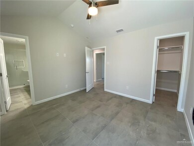 Unfurnished bedroom featuring a closet, a walk in closet, light tile floors, ceiling fan, and vaulted ceiling