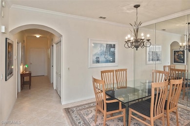 Dining area with arched walkways, ornamental molding, and light tile patterned flooring