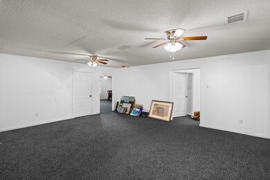 Unfurnished room featuring dark carpet, a textured ceiling, and a ceiling fan
