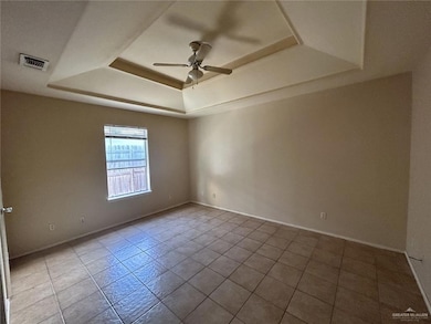 Tiled spare room featuring a raised ceiling and a ceiling fan