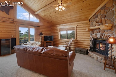 Living room with carpet, a fireplace, wood ceiling, high vaulted ceiling, and log walls