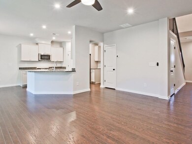 Kitchen with a ceiling fan, stainless steel microwave, recessed lighting, dark wood-style flooring, and white cabinetry