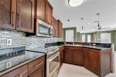 Kitchen with a sink, appliances with stainless steel finishes, a peninsula, ornamental molding, and visible vents
