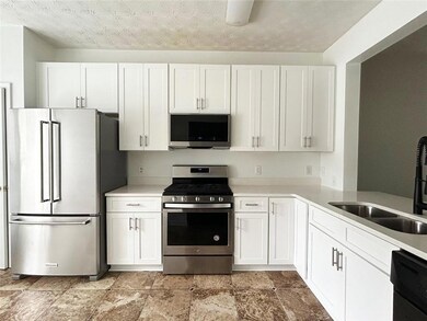 Kitchen with stainless steel appliances, white cabinets, and light countertops
