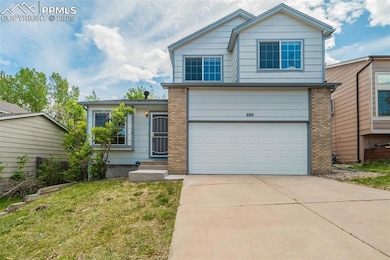View of front facade featuring concrete driveway, a garage, brick siding, and a front yard