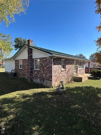 Back of house featuring brick siding, a lawn, and a chimney