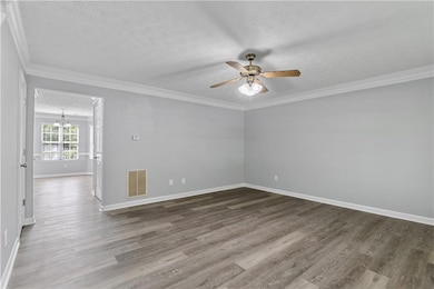 Unfurnished room featuring a textured ceiling, wood finished floors, crown molding, ceiling fan, and a chandelier