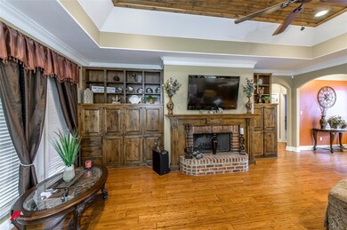 Living room with a tray ceiling, light hardwood / wood-style flooring, and a fireplace