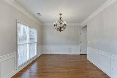 Unfurnished dining area featuring a decorative wall, a wainscoted wall, a chandelier, crown molding, and wood finished floors
