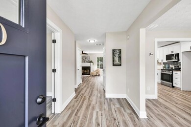 Foyer with light wood-style flooring, a fireplace, ceiling fan, and a textured ceiling