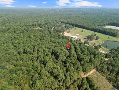 Aerial view of property and surrounding area with a heavily wooded area and a nearby body of water
