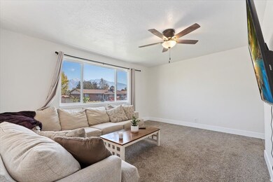 Living room with light carpet, a textured ceiling, and ceiling fan